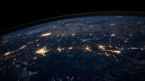 View of Earth from space showing illuminated cities at night.